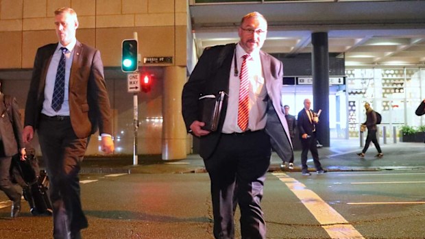 John Lyons (second right), Executive Editor of ABC News, watches as two Australian Federal Police officers cross the road outside the ABC building.