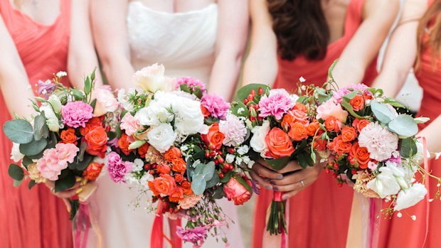Bridesmaids and bride holds bouquets of flowers in hand.
