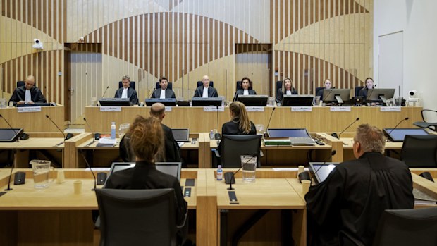 Presiding judge Hendrik Steenhuis, rear, fourth from left, opens the court session as the trial resumed at the high security court building at Schiphol Airport, near Amsterdam, Monday, June 8, 2020, for three Russians and a Ukrainian charged with crimes including murder for their alleged roles in the shooting down of Malaysia Airlines Flight MH17 over eastern Ukraine nearly six years ago.