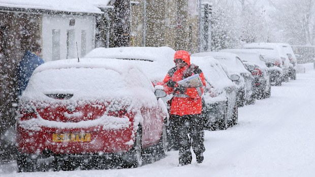 A postman struggles in the snow while making deliveries in Stirling, Scotland. (AAP)