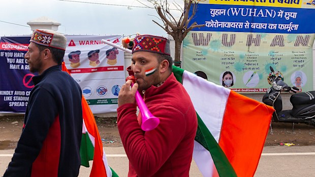 Indian fans walk past hoardings informing prevention of COVID-19 as they arrive to watch the first one-day international cricket match between India and South Africa in Dharmsala, India