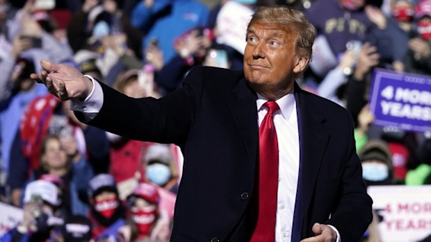 Donald Trump throws his face mask into the crowd before taking to the stage at the Pennsylvania rally.