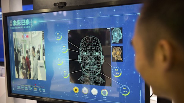 A man watches as a visitor tries out a facial recognition display at a booth for Chinese tech firm Ping'an Technology.