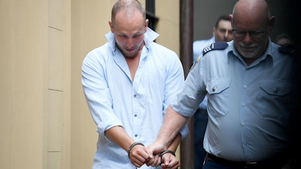 Russell Brian Wood is escorted to a Corrective Services van after his sentence hearing in the Supreme Court in Sydney.