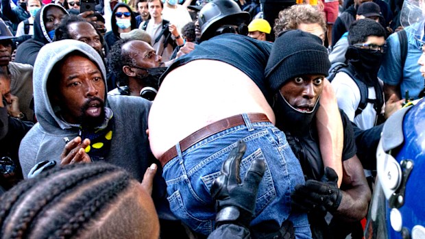 Patrick Hutchinson carries an injured man away after he was allegedly attacked by some of the crowd of protesters as police try to intervene on the Southbank near Waterloo station in London.