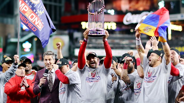 Manager Dave Martinez #4 of the Washington Nationals hoists the Commissioners Trophy after defeating the Houston Astros 6-2 