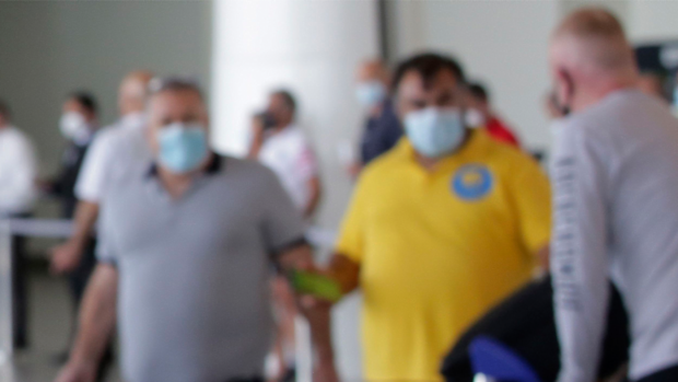 Blurred passengers at airport wearing face masks. 