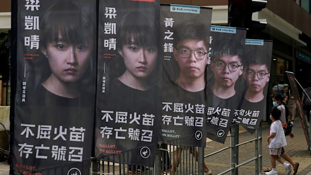 Banners of a pro-democracy candidate Joshua Wong, wearing glasses, are displayed outside a subway station in Hong Kong.