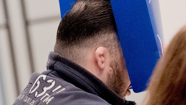 Former nurse Niels Hoegel covers his face as he enters the Weser-Ems Halle to attend his trial.