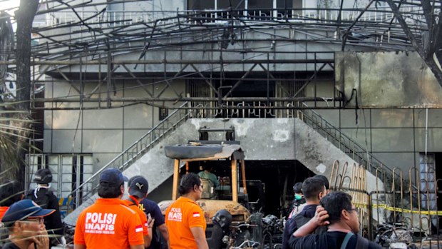 Indonesian police officers inspect the scene of a bomb blast in front of a church in Surabaya, East Java, Indonesia. (AP).