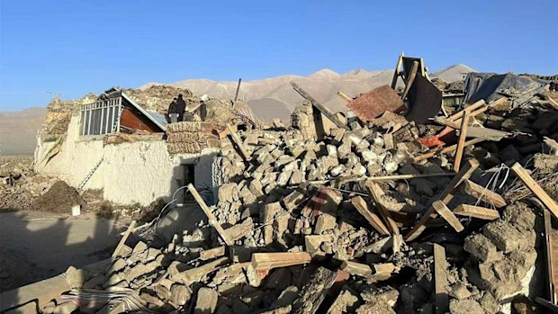 People stand amidst damaged houses in the aftermath of an earthquake in Tonglai Village, Changsuo Township of Dingri in Xigaze.