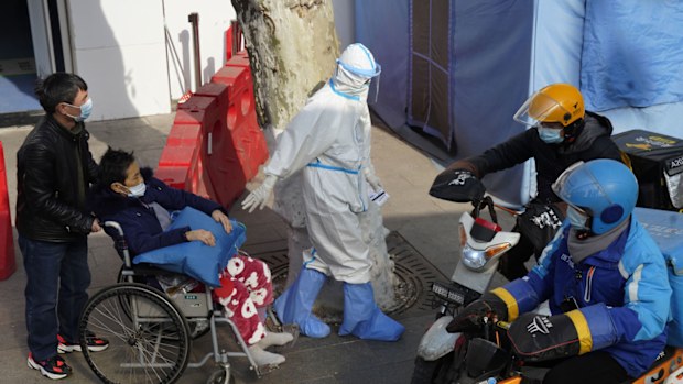 A medical worker in protector overall escorts a patient in wheelchair from the fever screening department of the Tongji Hospital which was at the frontline of the China's fight against the coronavirus in Wuhan in central China's Hubei province on Friday, Jan. 15, 2021