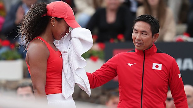 Naomi Osaka (L) of Japan reacts as her coach Toshihisa Tsuchihasi tries to comfort her during her match against Sara Sorribes Tormo of Spain