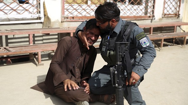An Afghanistan police officer comforts a grieving man after a terrorist attack on a maternity hospital in Kabul.