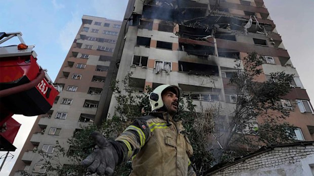 A firefighter calls out his colleagues at the scene of an explosion in a residence compound in northern Tehran, Iran.