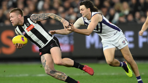 Jordan De Goey of the Magpies breaks free of a tackle by Jordan Clark of the Dockers during their semi final match.