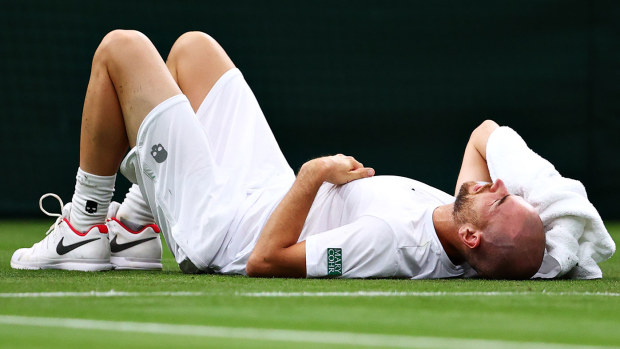 Adrian Mannarino of France reacts as he goes down with an injury in his Men's Singles First Round match against Roger Federer of Switzerland during Day Two of The Championships - Wimbledon.