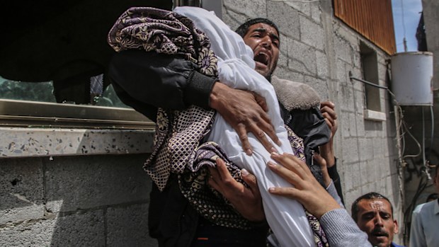 A Palestinian relative of a 14-month baby girl carries her body during her funeral.