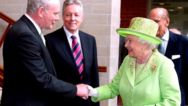 Queen Elizabeth II shakes hands with Northern Ireland Deputy First Minister and former IRA commander Martin McGuinness watched by First minister Peter Robinson, centre, at the Lyric Theatre in Belfast, Northern Ireland. (AAP)