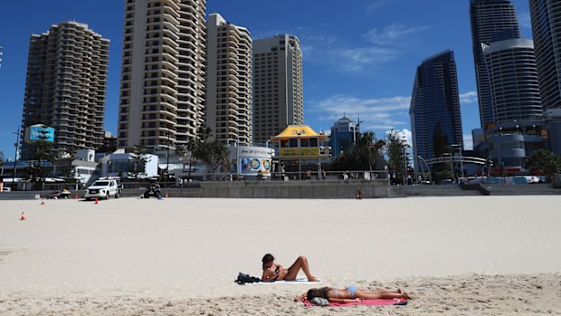 People lie on the beach at Surfers Paradise beach in Gold Coast, Australia.
