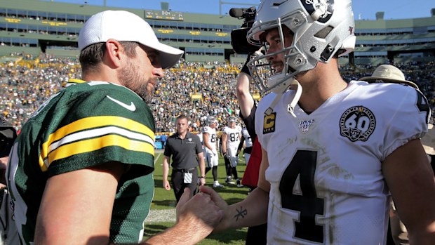 Aaron Rodgers #12 of the Green Bay Packers and Derek Carr #4 of the Oakland Raiders meet
