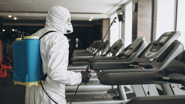 A worker in a protective suit cleans exercise equipment. The Centres for Disease Control, on Monday, April 19, 2021, said the risk of surface transmission of COVID-19 is low.