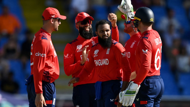 Adil Rashid takes a wicket against Oman, with England teammates congratulating the spinner.