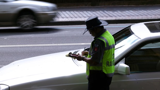 A parking inspector issues a ticket to a car parked on Macquarie Street in Sydney's CBD.