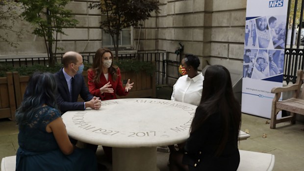 Prince William and his wife Kate the Duchess of Cambridge meet pharmacist Joyce Duah, second right, and pharmacy technicians Amelia Chowdhury, right, and Dipal Samuel, left, as they visit St. Bartholomew's Hospital in London, to mark the launch of the nationwide 'Hold Still' community photography project, Tuesday, Oct. 20, 2020