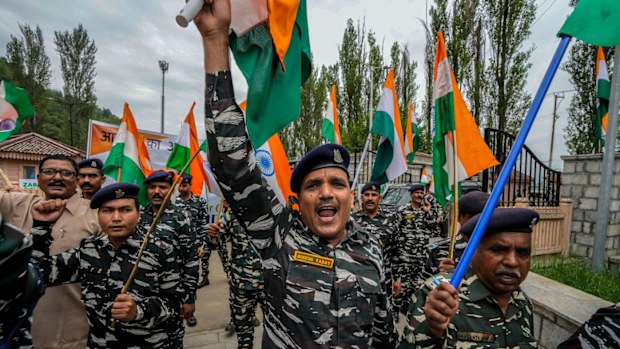 Indian paramilitary officers hold national flags and shout slogans as they march in a rally