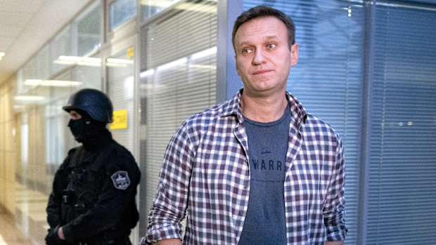 n this Dec. 26, 2019, file photo, Russian opposition leader Alexei Navalny speaks to the media in front of a security officer standing guard at the Foundation for Fighting Corruption office in Moscow, Russia. 
