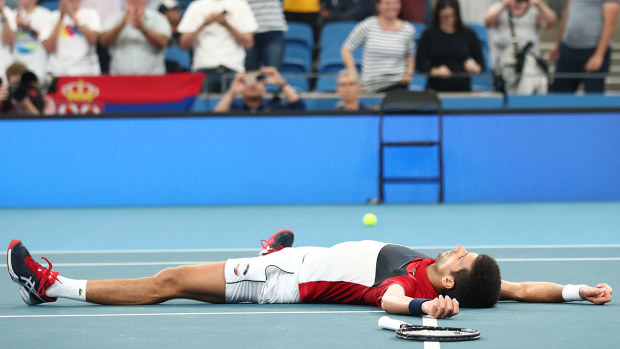 Novak Djokovic of Serbia lays on the court celebrating match point during his semi-final singles match against Daniil Medvedev