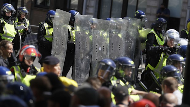 British police officers in riot gear scuffle with members of far-right groups protesting against a Black Lives Matter demonstration, in central London, Saturday, June 13, 2020.