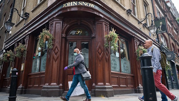 A person wearing a protective face mask walks past a temporarily closed pub named after the founding father of epidemiology John Snow, on June 19, 2020 in London, England.