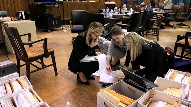 Attorneys Lindsay Runnels and Kylie Mank and paralegal Maci Morgan search through boxes of exhibits before court restarts after a break for lunch during the fourth day of Lamar Johnson's wrongful conviction hearing.