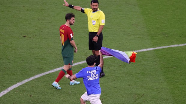 Play is stopped in the Uruguay-Portugal match as a pitch invader holding a rainbow flag invades the field.