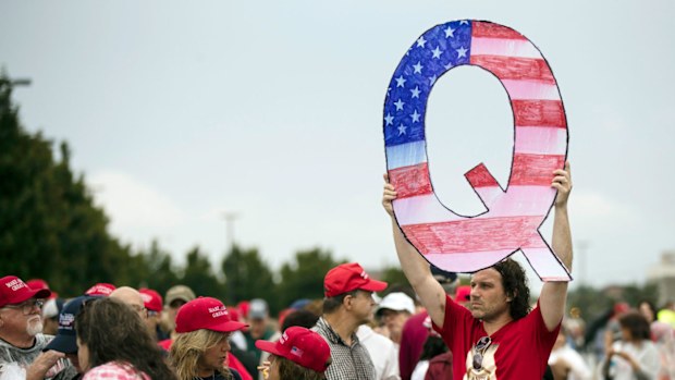 A protesters holds a Q sign waits in line with others to enter a campaign rally with President Donald Trump in August 2014.