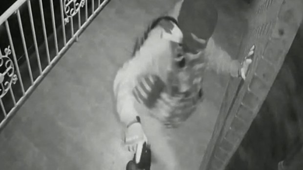 The moment the gunman dressed in military clothing and a balaclava approaches the property with a hand gun