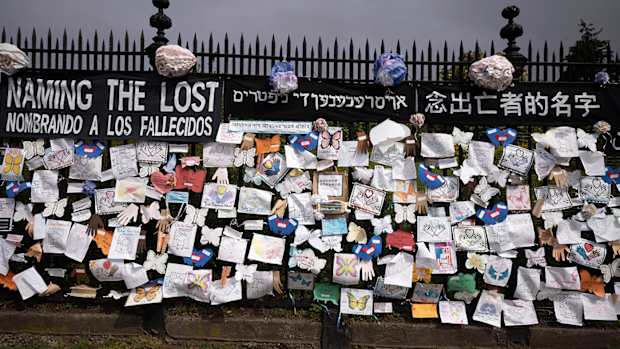 FILE - In this Thursday, May 28, 2020 file photo, a fence outside Brooklyn's Green-Wood Cemetery is adorned with tributes to victims of COVID-19 in New York. 