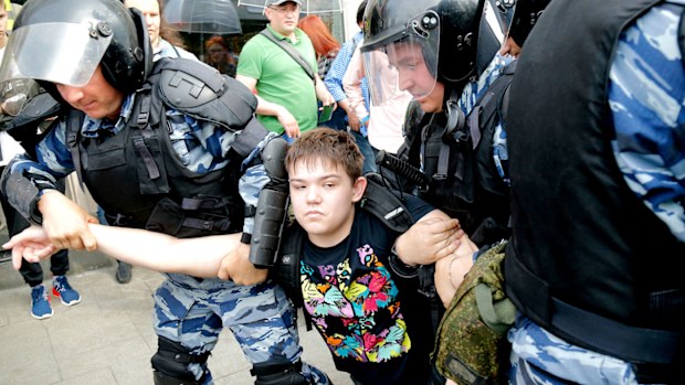 A young demonstrator is apprehended by riot police during a demonstration in downtown Moscow. (AAP)
