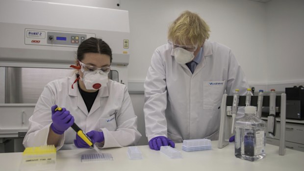 Britain's Prime Minister Boris Johnson with quality control technician Kerri Symington, visits the French biotechnology laboratory Valneva in Livingston, Scotland, Thursday Jan. 28, 2021, where they will be producing a COVID-19 vaccine on a large scale, during a visit to Scotland. 