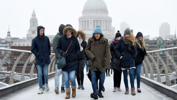 People walk across the Millennium Bridge as snow falls in London. (AAP)