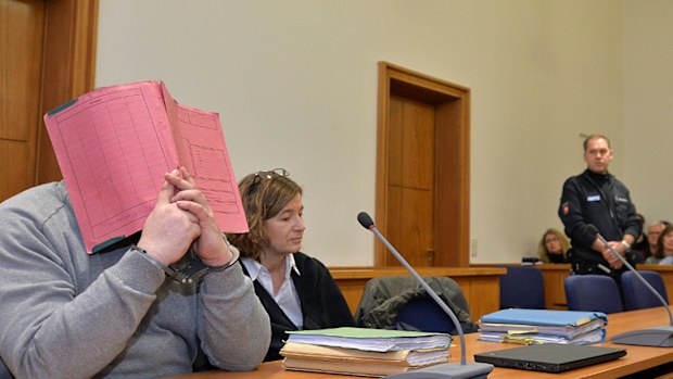 Former nurse Niels Hoegel, accused of multiple murder and attempted murder of patients, covering his face with a file at  during an earlier hearing at the district court in Oldenburg, Germany. (Photo: AP)./