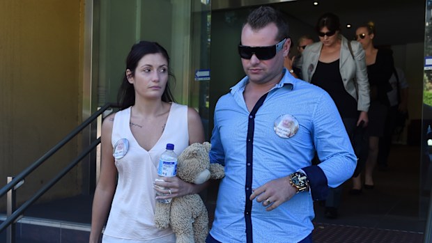 Naomi Day, mother of 6-month-old Kyran, leaves the Glebe Coroners Court clutching a teddy bear with her husband Grant. (AAP)