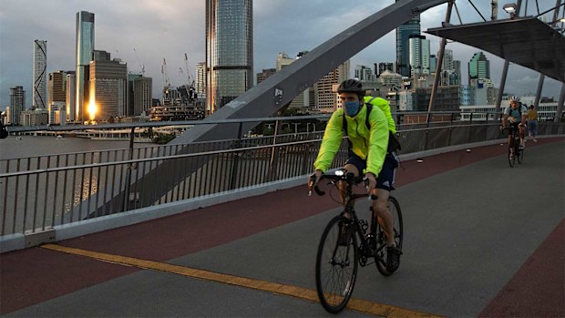 A masked cyclist travels along Southbank in Brisbane.
