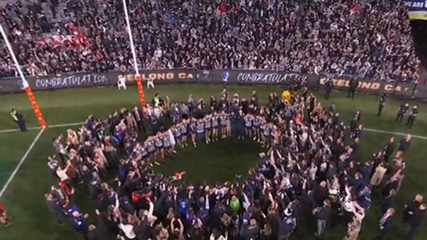 Geelong players sing the theme song in front of their fans at the MCG after the premiership win