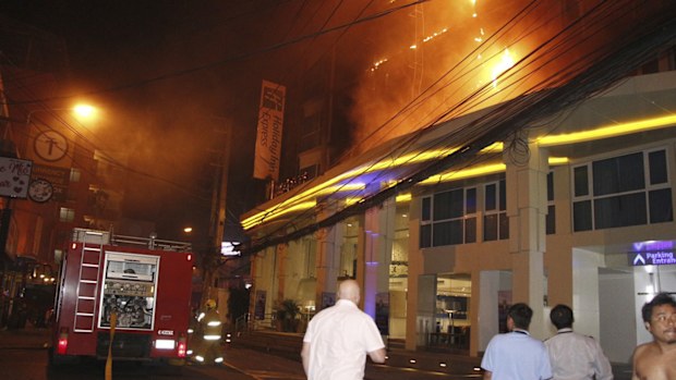 Tourists watch as a fire rages on the upper floors at the Holiday Inn Express Hotel in Pattaya, Chonburi province, Thailand, Friday, Dec. 6, 2019. 