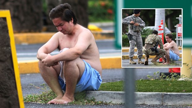 An unidentified male sits outside Pearl Harbour naval base after a fatal shooting.