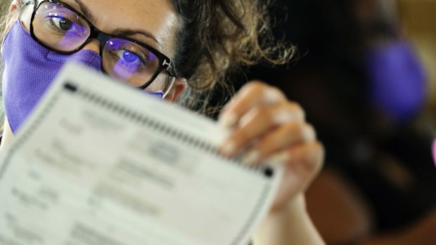 An election worker examines ballots as vote counting in the general election continues at State Farm Arena on Thursday, Nov. 5, 2020, in Atlanta