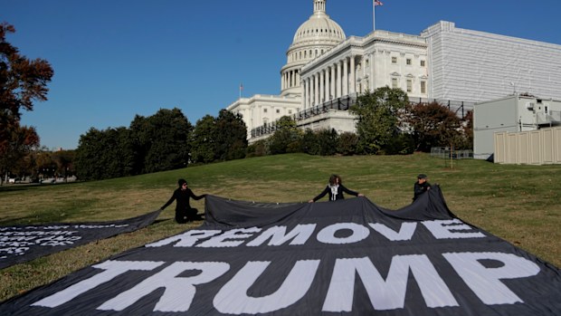 Demonstrators kneel near large banners on the lawn adjacent to the US Capitol.